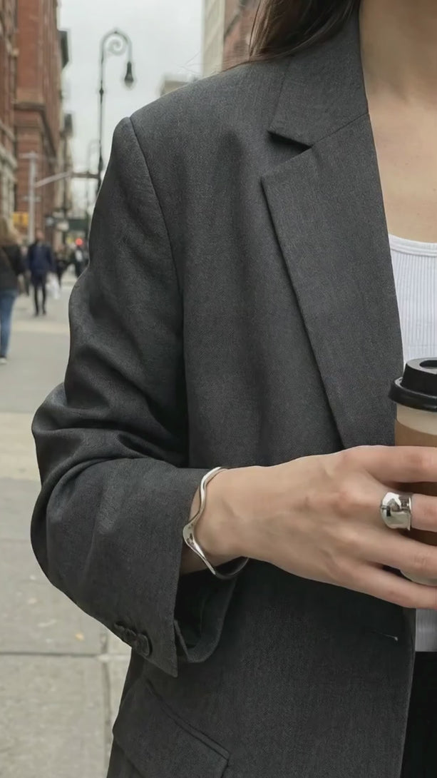 Model walking down a city street wearing the modern 925 silver wavy cuff and ring set in a casual stylish outfit.