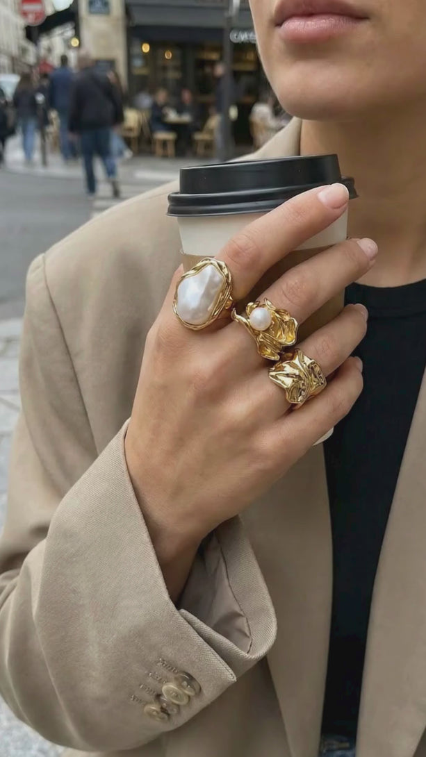 Close-up of a model's hand wearing the complete 3-piece molten ring set in gold, showcasing a bold, high-fashion sculptural look.