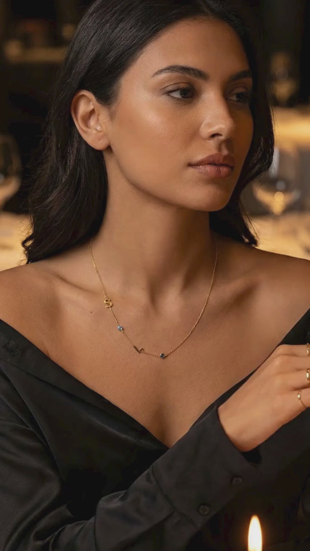 Short video of a model wearing the custom spaced letter and birthstone necklace, demonstrating the sparkling movement of the charms and the adjustable chain fit.