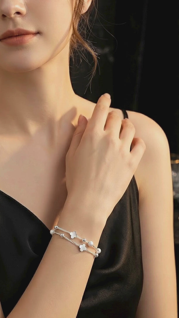 A stylish video showing a woman in a high-fashion black evening dress wearing the S999 fine silver lucky clover bracelet, highlighting the sparkling stones and spinning transfer beads.